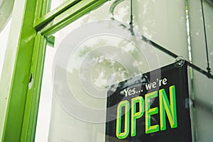 A business sign that says Ã¢â¬ËOpenÃ¢â¬â¢ on cafe or restaurant hang on door at entrance.